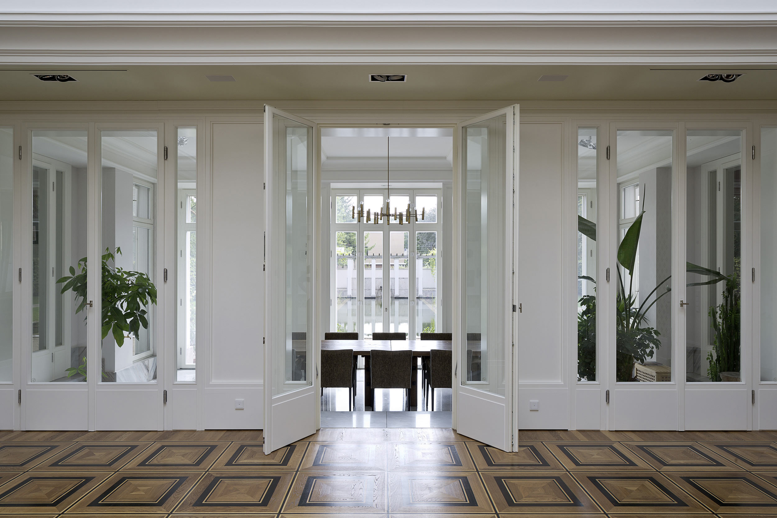 Neubau einer Villa im neoklassizistischen Stil - Der Durchgang zur Gartenorangerie mit Terrazzoboden und versenkbaren Fenstern