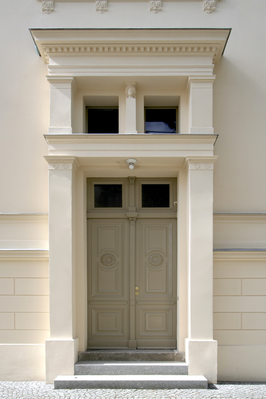 Das Eingangsportal prägt in in klassizistischer Zurückhaltung die Doppelflügeltür mit darüber liegenden Oberlichtern.