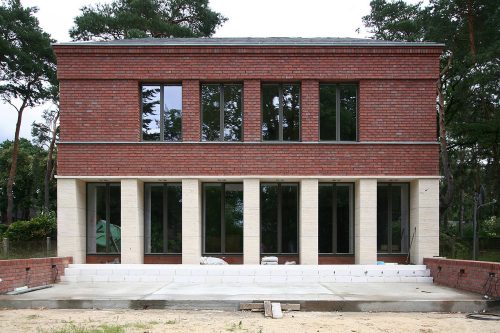 Die Gartenansicht ist mit Travertinsockel und einer Lochfassade aus Backstein.